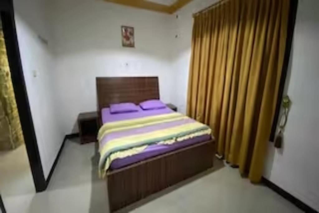 a small bedroom with a bed with purple pillows at EXPRESS O 91923 Homestay Zona in Sukabumi