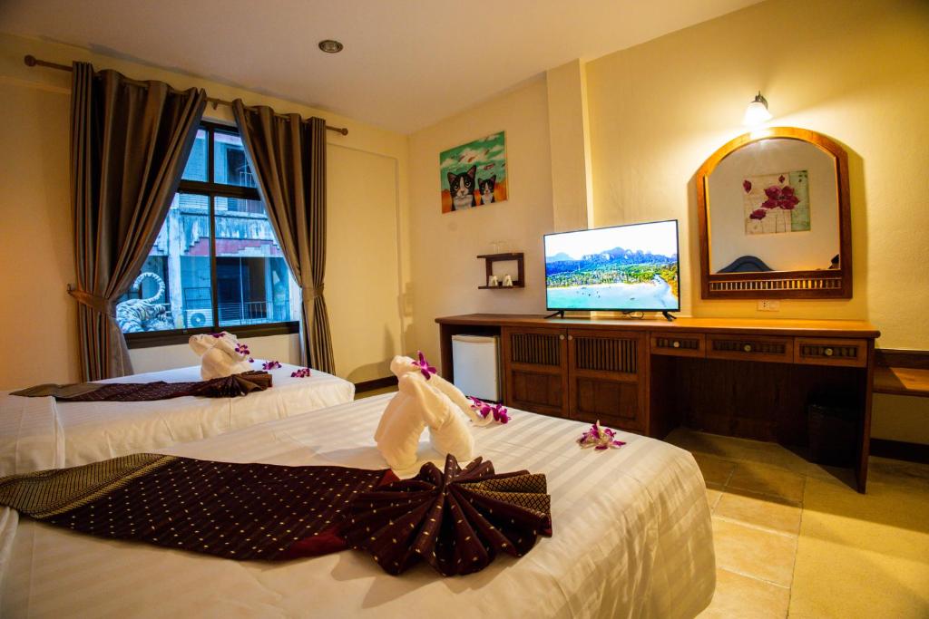 パトンビーチにあるRico's Patong Hotelのベッド2台、薄型テレビが備わるホテルルームです。