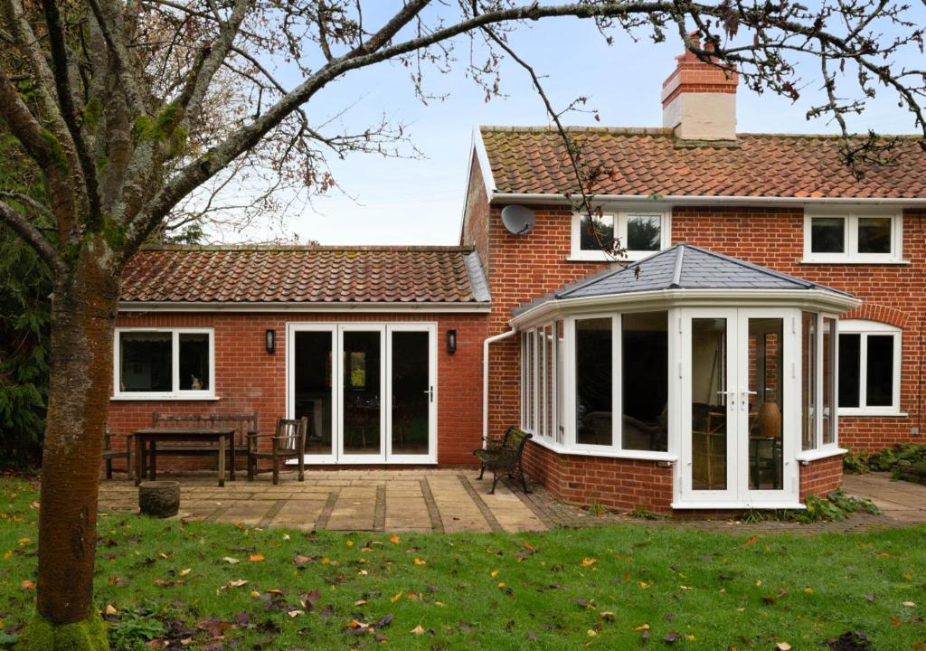 a brick house with a conservatory and a patio at The Pightle in Parham