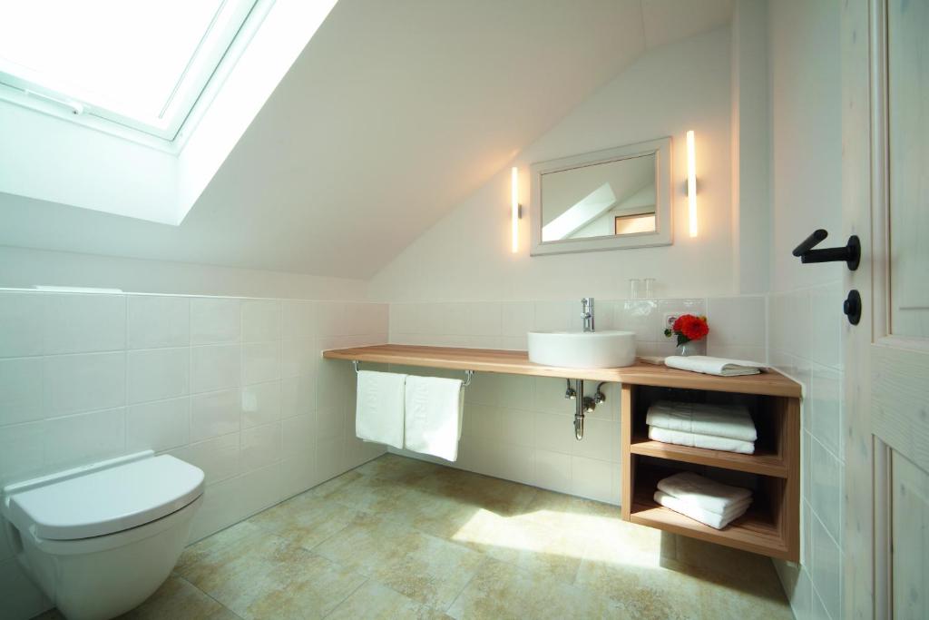 a bathroom with a toilet and a sink and a mirror at Gasthof Neuwirt Unterföhring in Munich