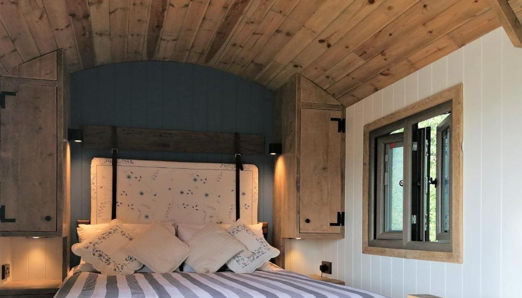 The Huddle at Big Sky Brisley في Brisley: غرفة نوم بسرير كبير بسقف خشبي
