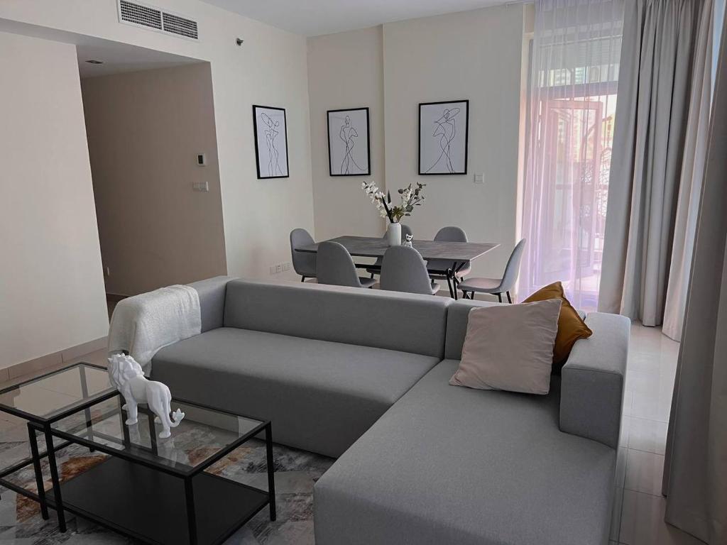 uma sala de estar com um sofá cinzento e uma mesa em Huge terrace with canal view & hotels beach access available no Dubai