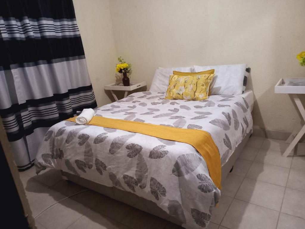 a bedroom with a bed with a yellow and gray blanket at Tangwe Guest House 