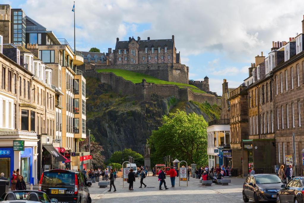 a busy city street with a castle in the background at Luxury Modern 3 Bedroom Apartment in City Centre in Edinburgh