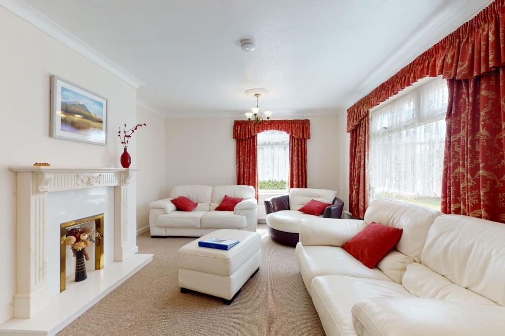 a living room with white furniture and red curtains at Alberts Retreat in Abergele