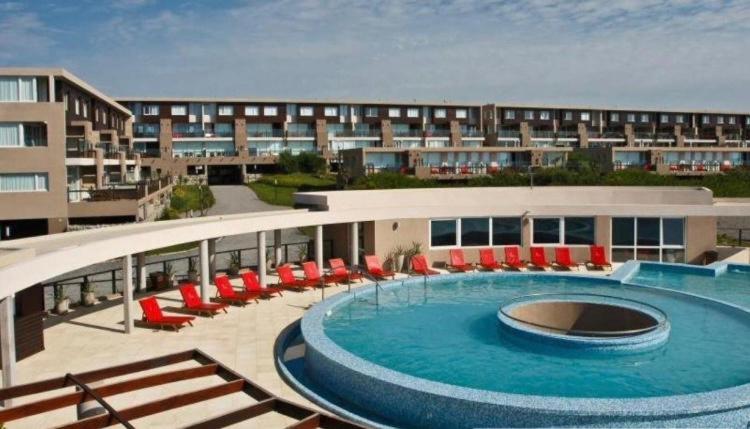 duży budynek z basenem i czerwonymi krzesłami w obiekcie Linda Bay Beach & Resort Studio 304 w mieście Mar de las Pampas
