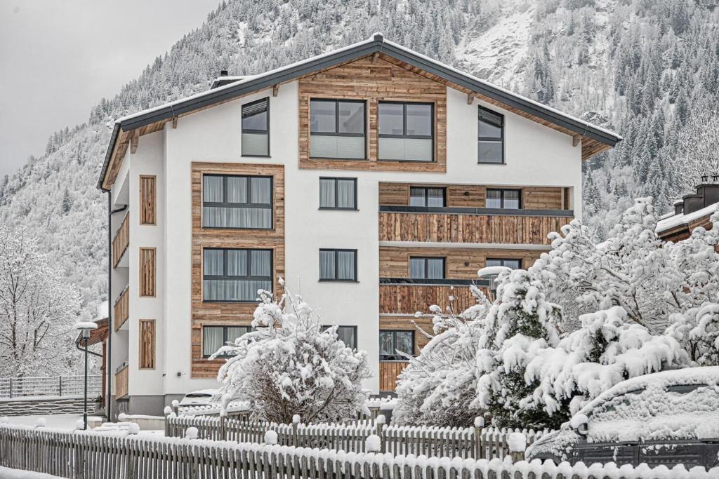 een huis in de sneeuw met een hek bij Apartment NH96 inklusive kostenfreiem Eintritt in die Alpentherme in Bad Hofgastein