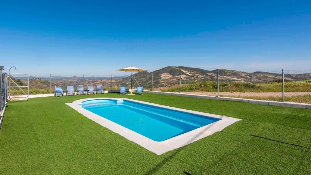 una piscina en un césped con sillas y sombrilla en Casa Rural Olvera by Ruralidays en Olvera