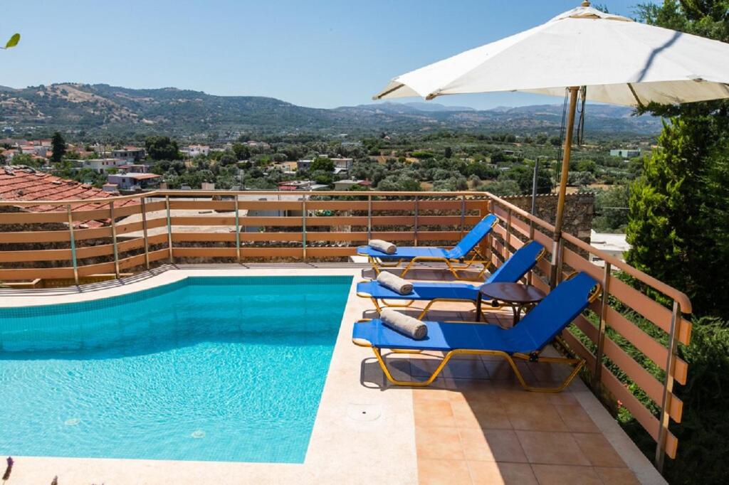 a swimming pool with chairs and an umbrella at Bezari pool villa in Metochia Fratzeskiana