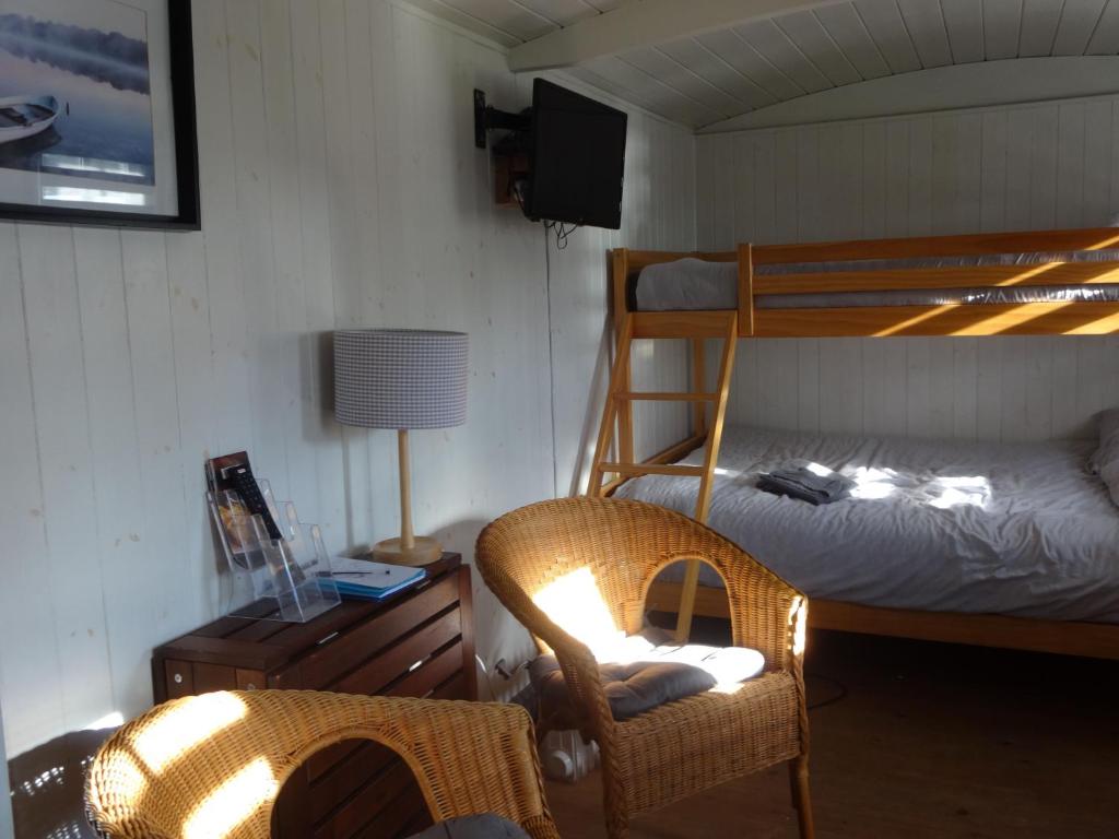 a bedroom with a bunk bed and a chair at Shepherds Hut, Hannahs Retreat, Bowness-on-Solway in Bowness-on-Solway