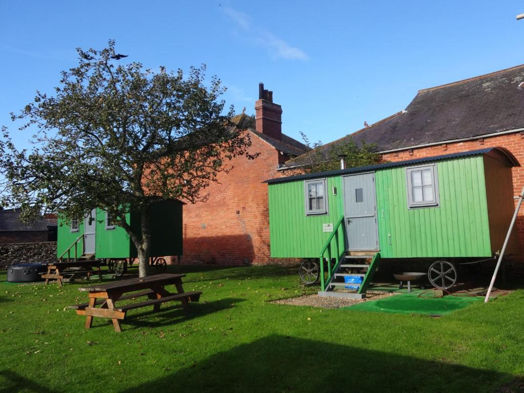 un patio con dos edificios verdes y una mesa de picnic en Sian's Retreat, en Bowness-on-Solway