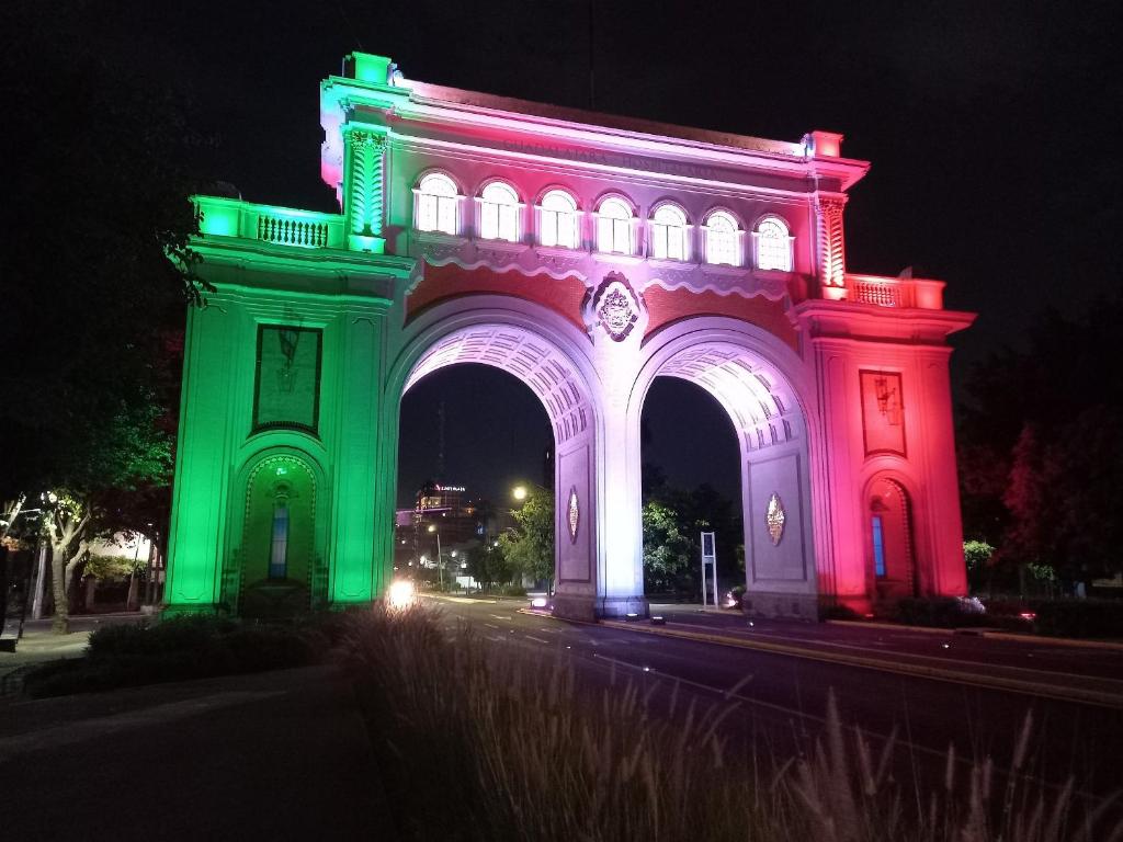 un gran edificio iluminado en verde y blanco en Tu Estancia Guadalajara, en Guadalajara