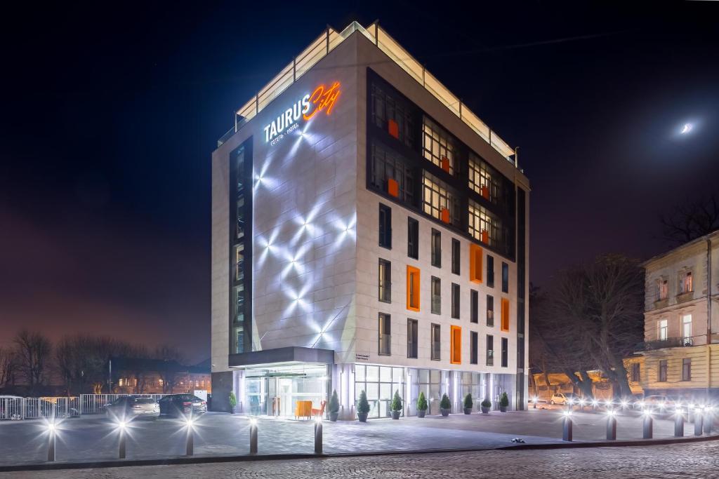 a building with a sign on it at night at Taurus City Hotel in Lviv