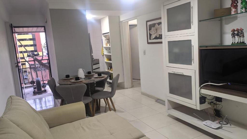 uma sala de estar com um sofá, uma televisão e uma mesa em Flat Mobiliado na Ponta Verde em Maceió