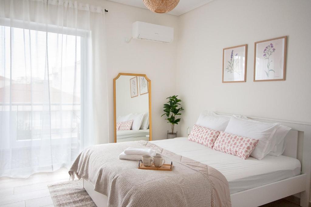 a white bedroom with a large bed with a mirror at La Petite Fleur Guesthouse in Xylokastron