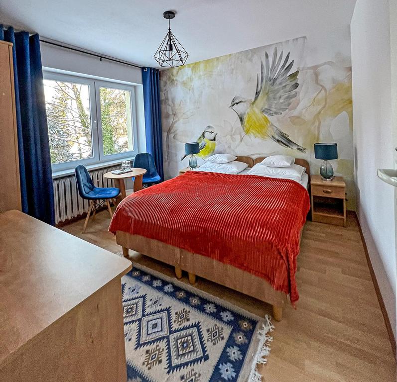 Un dormitorio con una cama roja con una pintura en la pared en Willa RADosna, en Karpacz