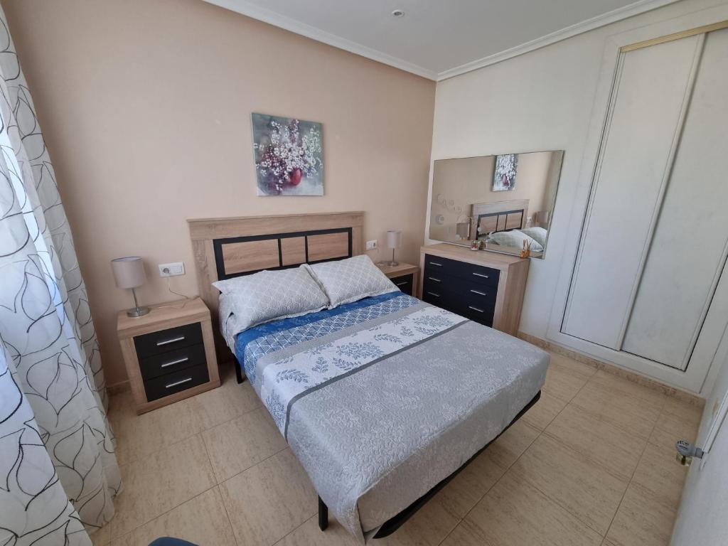 ein Schlafzimmer mit einem Bett mit zwei Nachttischen und einem Spiegel in der Unterkunft casa el Eden nudista in Playas de Vera