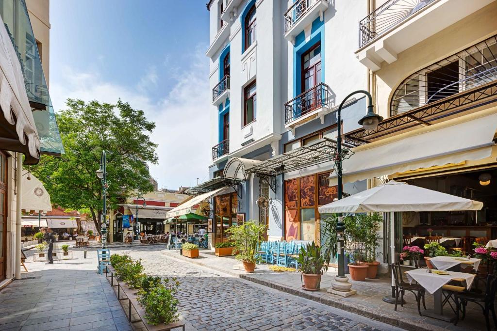 eine leere Straße mit Tischen, Stühlen und Gebäuden in der Unterkunft Colors Ladadika Thessaloniki in Thessaloniki