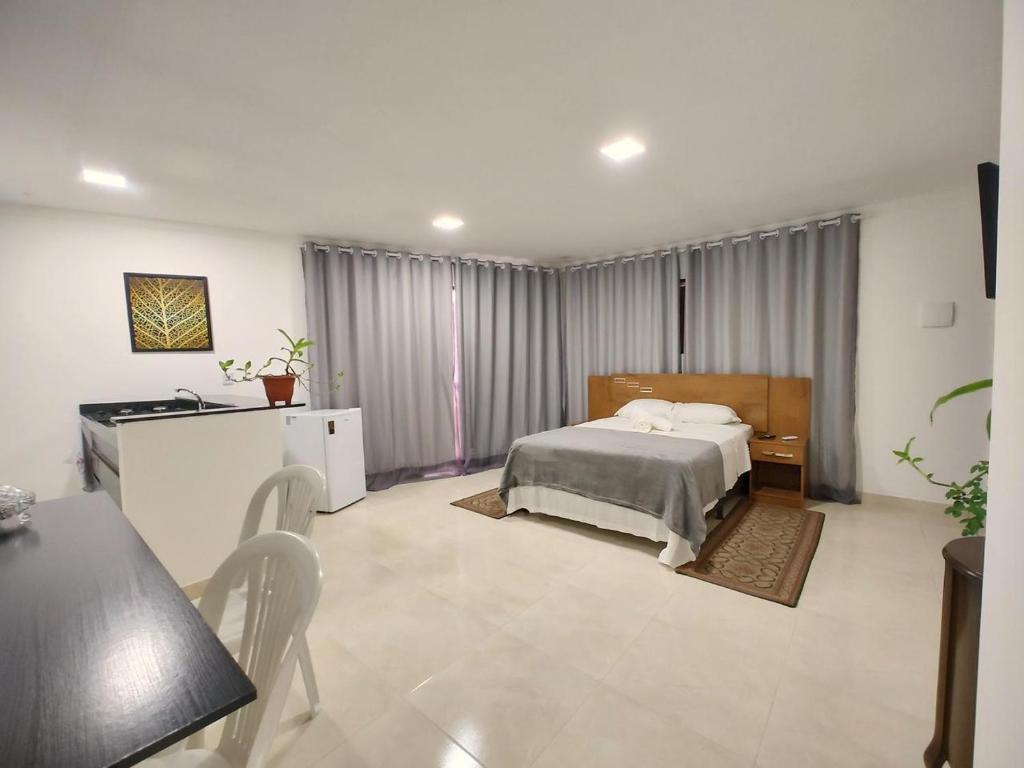 Flats Paraíso Louveny في جاباراتينغا: غرفة نوم بسرير وطاولة وكراسي
