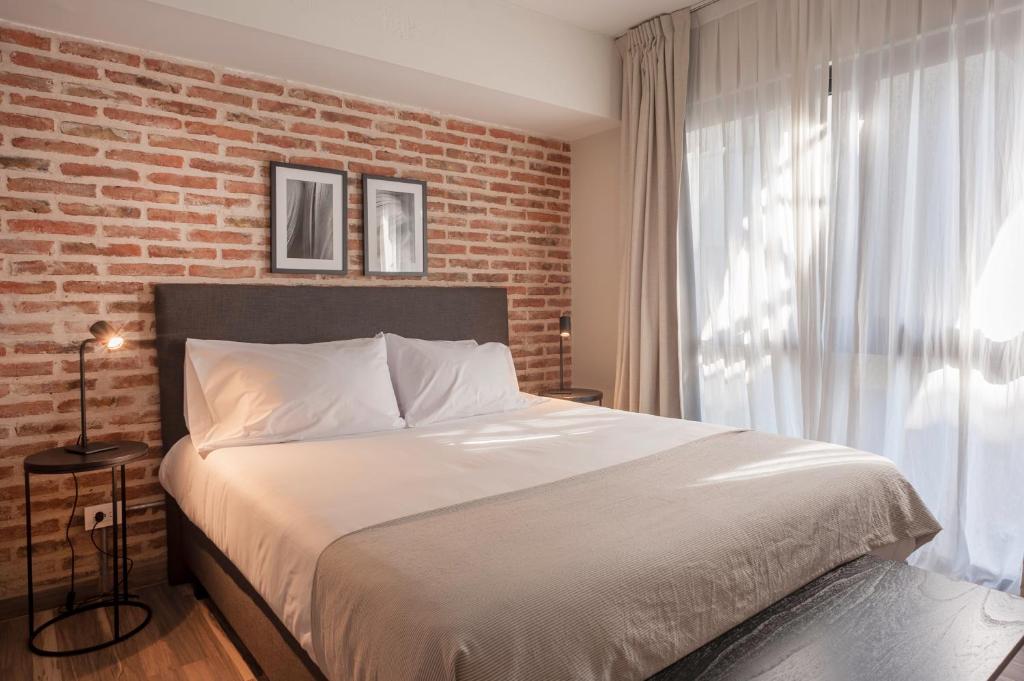 1 dormitorio con 1 cama grande y pared de ladrillo en Viví este Increíble Nuevo Depto en San Telmo -332- en Buenos Aires