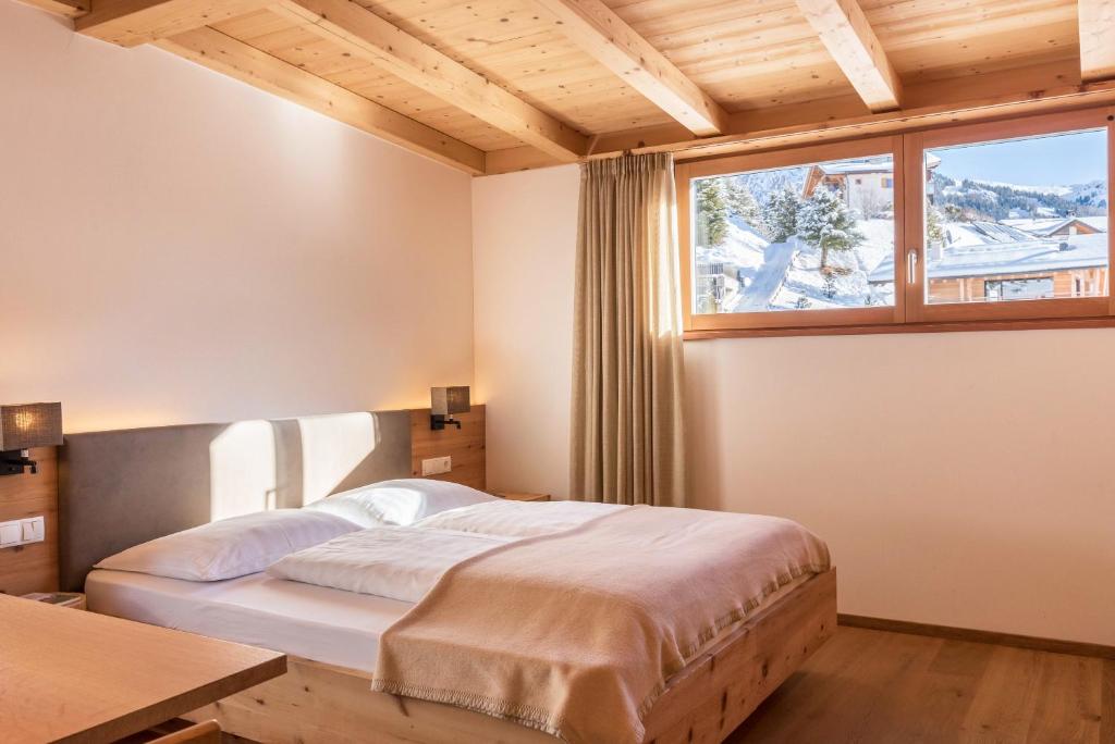 a bedroom with a bed and a large window at Villa Solinda App Rossini in Selva di Val Gardena