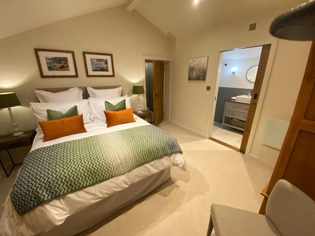 une chambre avec un grand lit avec des oreillers orange et verts dans l'établissement Gower Villa Luxury Cottage, 2 bedroom en-suite with Hot Tub, à Clynderwen