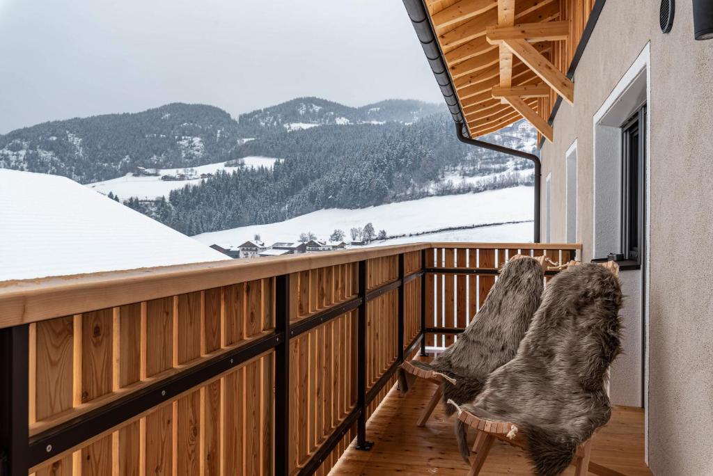 2 Stühle auf einem Balkon mit Bergblick in der Unterkunft Planerhof Apartment Enzian in Villnöss