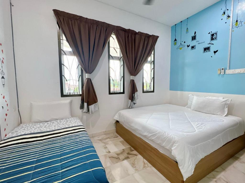 Duas camas num quarto com paredes e janelas azuis em Ks Homestay em Taiping