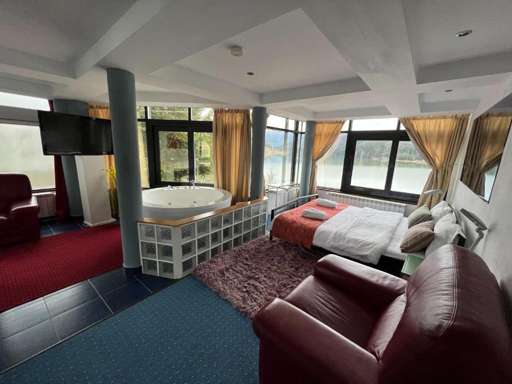 1 dormitorio con bañera, cama y sofá en Vila Franceză - Cazare cu jacuzzi pe malul lacului Colibița en Colibiţa