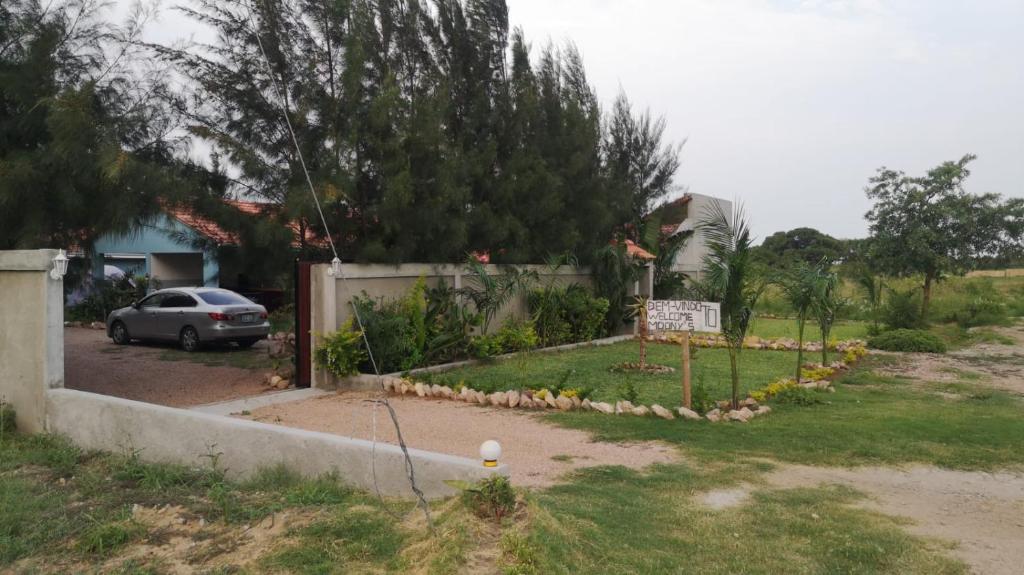 a driveway with a sign in a yard with a car at Moony’s Chalets & Camping in Catembe