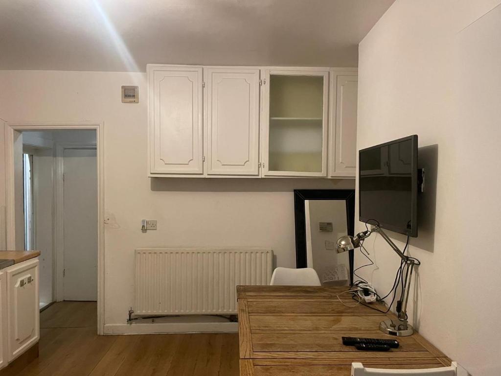 ロンドンにあるBalham, South London Spacious Guest House 3の白いキャビネット付きのキッチン、テレビ付きのデスクが備わります。