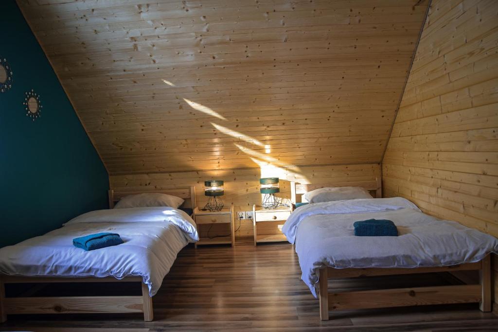 two beds in a room with wooden walls at Leśna Ostoja in Lubawka