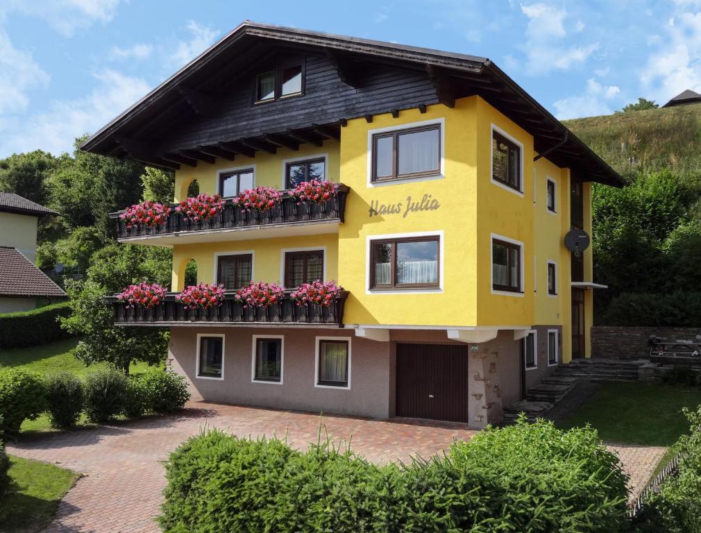 a yellow house with flowers on the balcony at Ferienwohnung Haus Julia in Mariapfarr