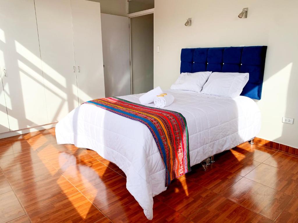 Schlafzimmer mit einem großen weißen Bett mit blauem Kopfteil in der Unterkunft STYLISH & Spacious Apartment in Cusco