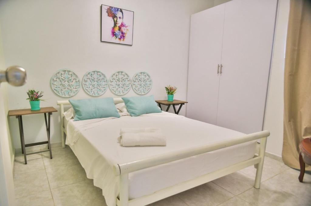 een slaapkamer met een groot wit bed met blauwe kussens bij 2CB-4 APARTAMENTO DE 2 ALCOBAS EN EL CENTRO HISTORICO CON AIRE ACONDICIONADO Y WIFI in Cartagena
