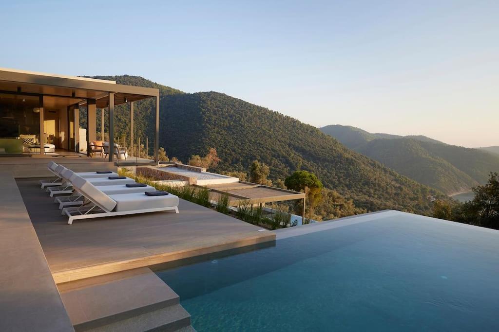 a house with a swimming pool with mountains in the background at Ohlive II sea view Kechria in Skiathos Town