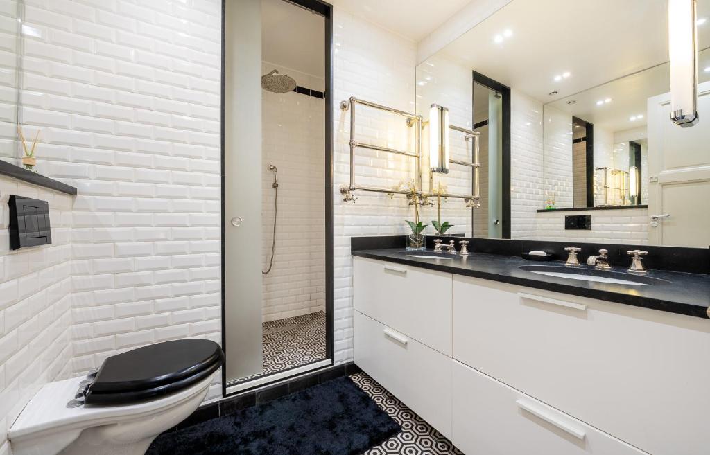 a white bathroom with a toilet and a sink at Spacieux et élégant appartement Porte des ternes in Paris