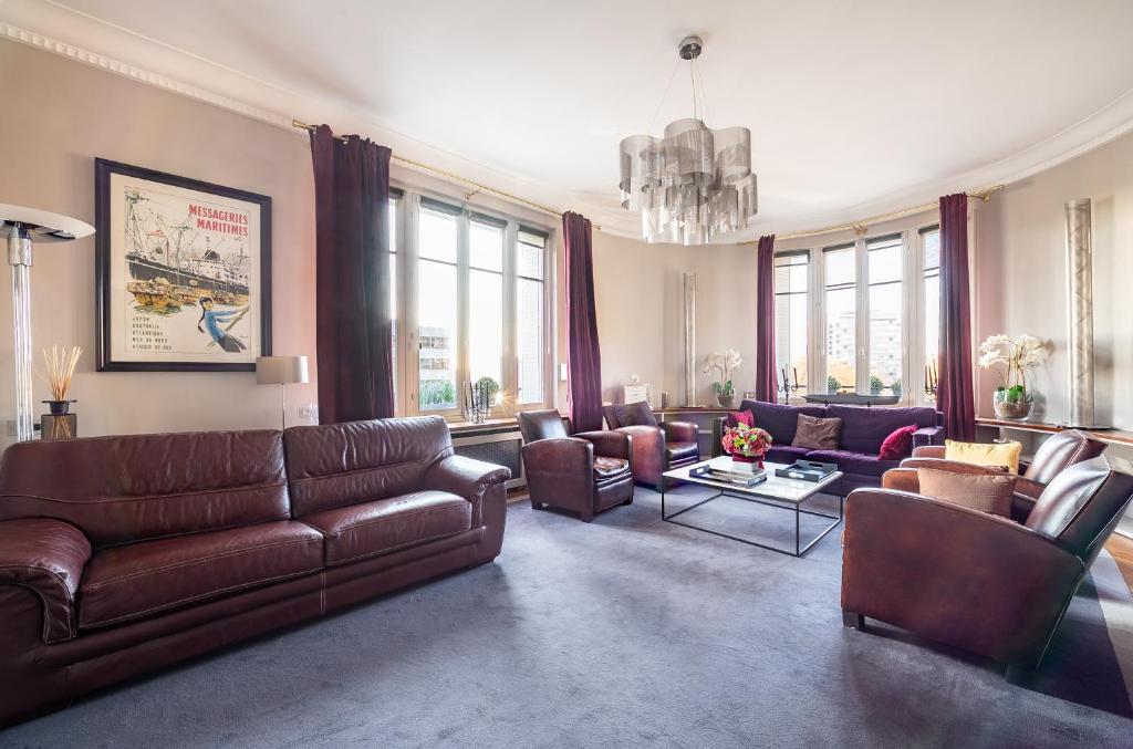 a living room with brown leather furniture and windows at Spacieux et élégant appartement Porte des ternes in Paris