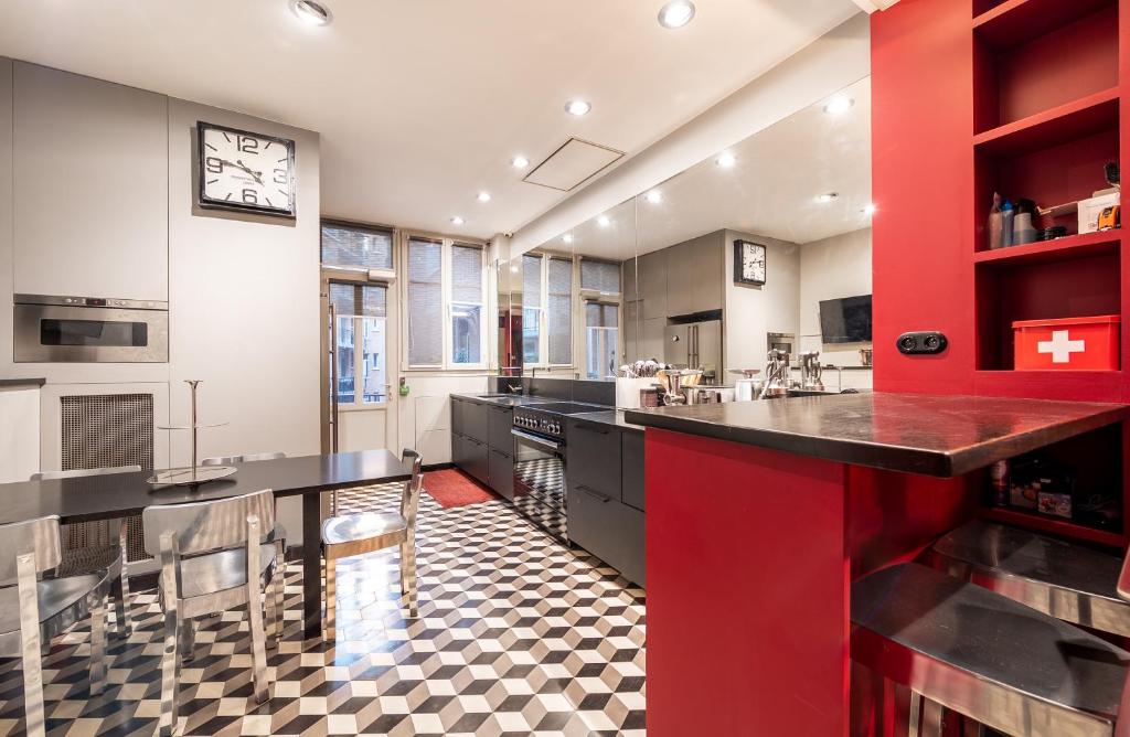 a kitchen with black countertops and a red wall at Spacieux et élégant appartement Porte des ternes in Paris