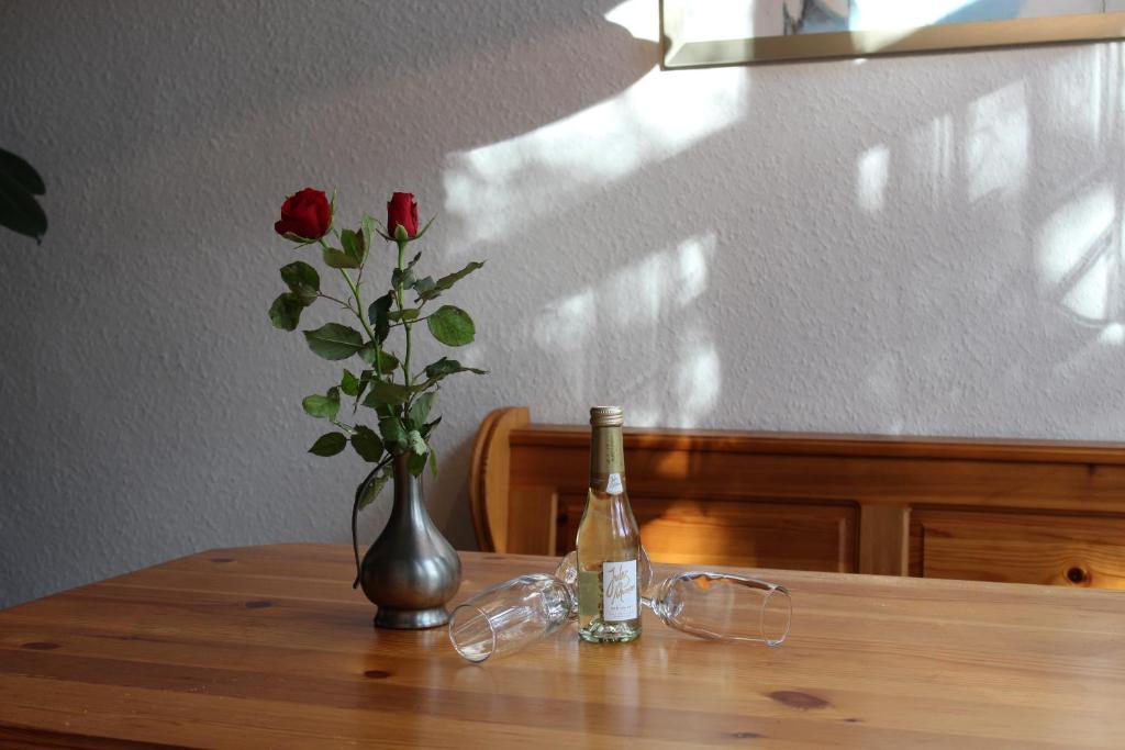 eine Flasche Wein und eine Vase mit einer Rose auf dem Tisch in der Unterkunft Eine Quelle der Ruhe und Erholung in Nettersheim