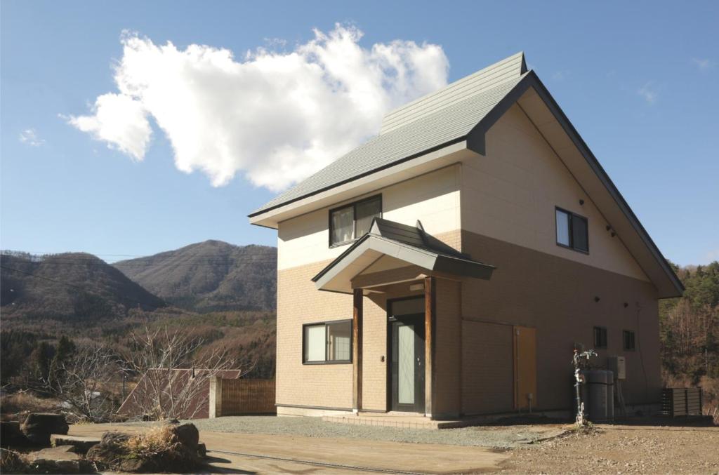una pequeña casa con montañas en el fondo en Active House Ryuo - Vacation STAY 04019v, en Shimotakai