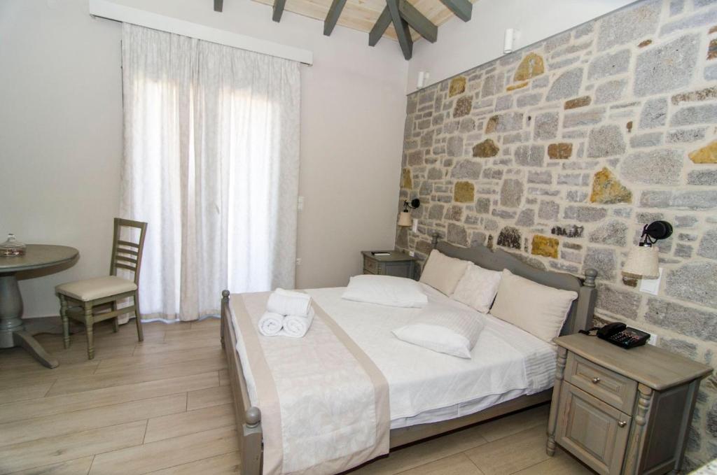 a bedroom with a bed and a stone wall at Amigdalies in Myrina
