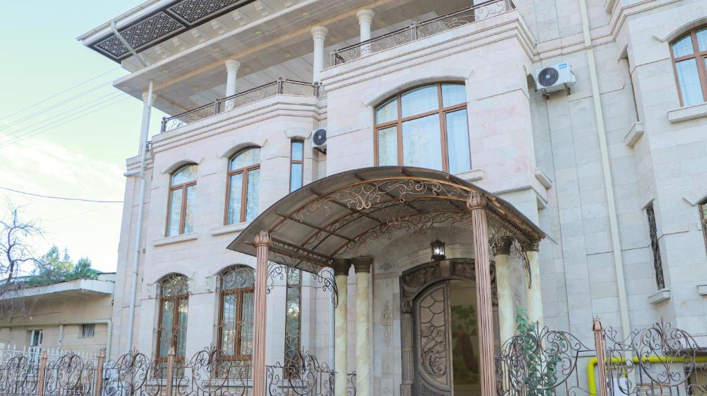 un grande edificio bianco con un cancello di fronte di Prestige Terrace Hotel a Bukhara