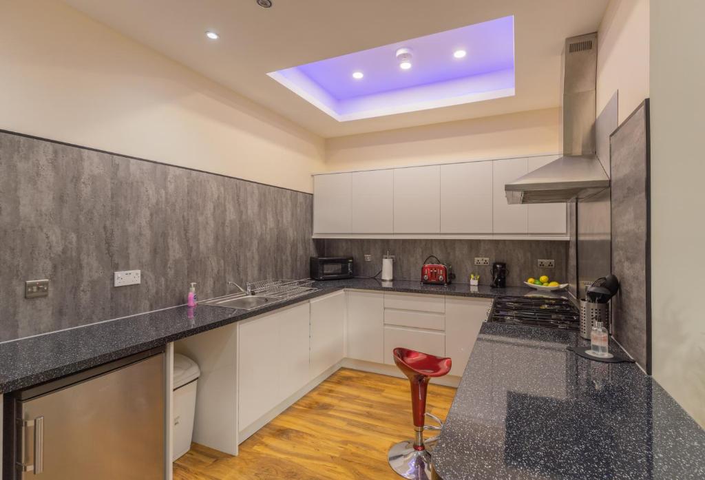 une cuisine avec des placards blancs et un tabouret rouge dans l'établissement New 3-Bedroom Apartment Close to City Centre, à Édimbourg
