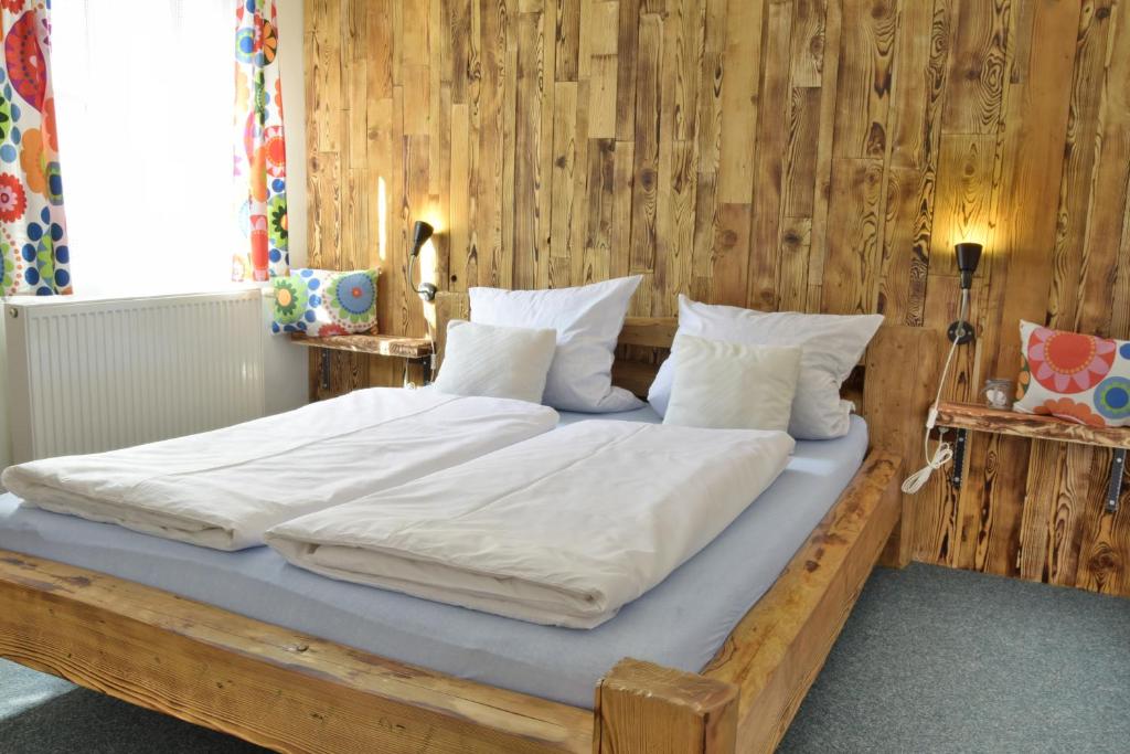 Elle comprend un grand lit en bois avec des draps et des oreillers blancs. dans l'établissement Apartmány Černý Důl, à Černý Důl
