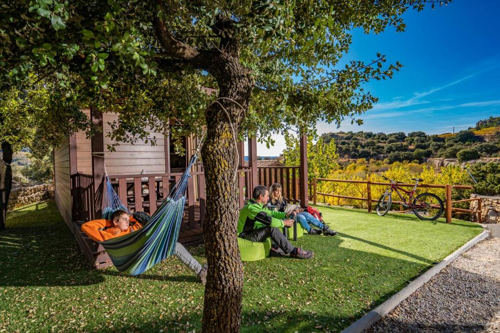 un grupo de personas sentadas en una hamaca bajo un árbol en Camping Bungalow Serra de Prades Resort, en Vilanova de Prades
