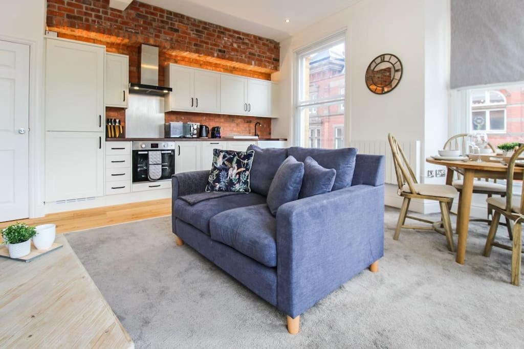 a living room with a blue couch and a kitchen at Luxurious City Centre Lace Market Apartment in Nottingham