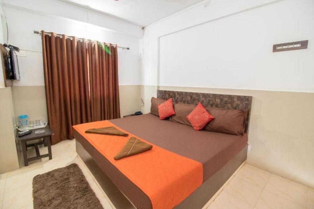 a bedroom with a bed with orange sheets and red pillows at GRG Traveller in Panaji