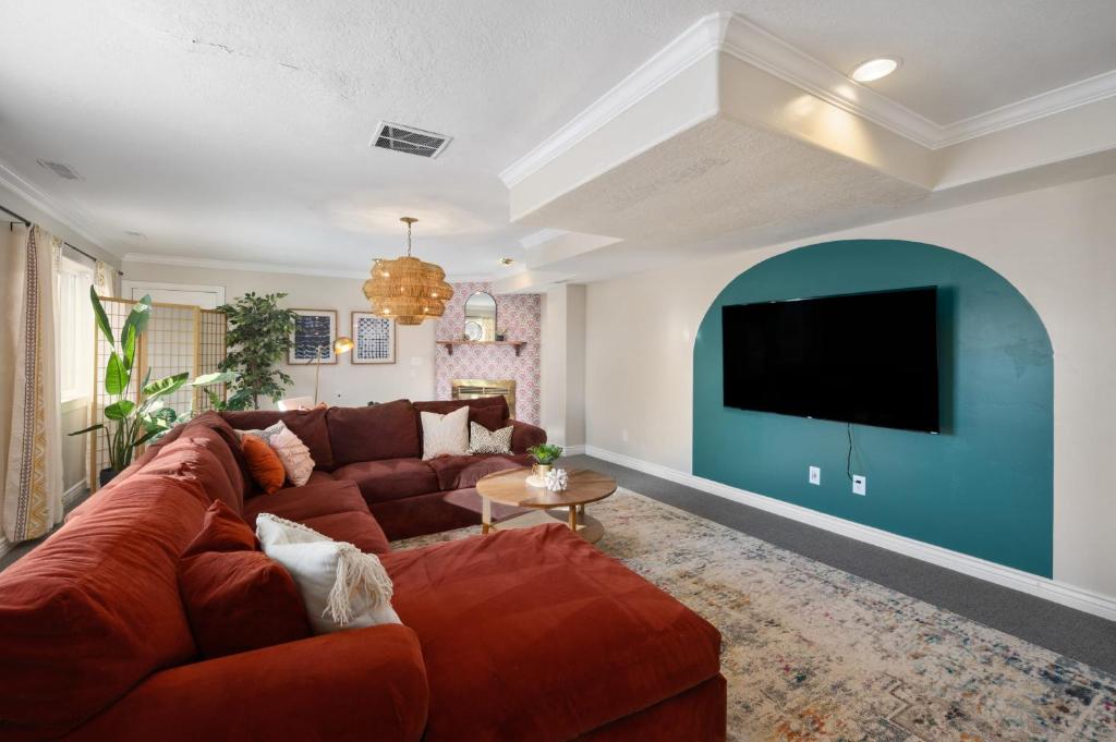 uma sala de estar com um sofá castanho e uma televisão de ecrã plano em Bohemian LARGE Family Home Perfect for Groups em Orem