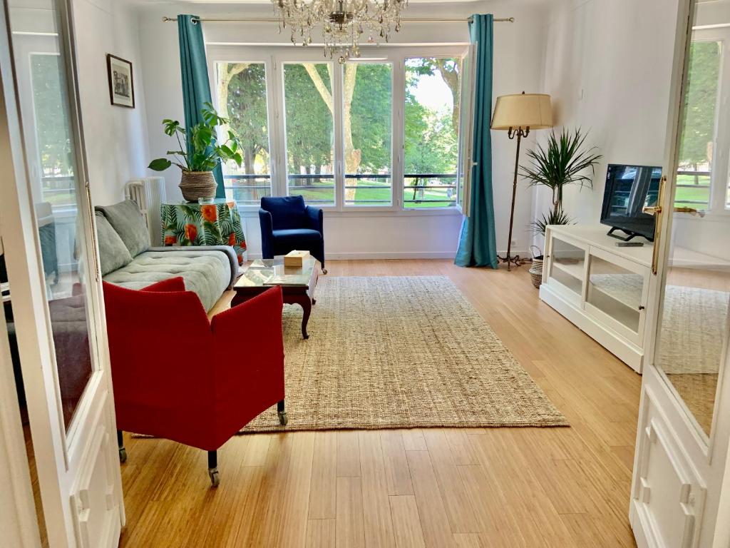 een woonkamer met een rode stoel en een bank bij GRAND Appartement 85m2 centre ville de BIARRITZ 6 pers in Biarritz
